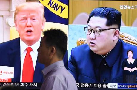 Un hombre pasa frente a una pantalla de televisión que muestra al presidente estadounidense Donald Trump (izq.) y al líder norcoreano Kim Jong Un (der.) en una estación de tren. Foto: AFP