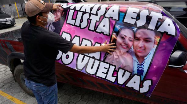 Miguel Ángel Taque,  con una pancarta para su novia Yoselin Solorzano, quien realiza cuarentena en un hotel de Guatemala después de dar positivo al covid-19. Foto: AFP
