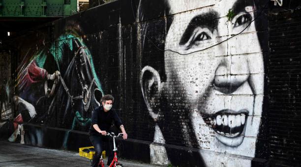 Un hombre transita en bicicleta junto a un mural de Carlos Gardel en Buenos Aires, Argentina. Foto: AFP