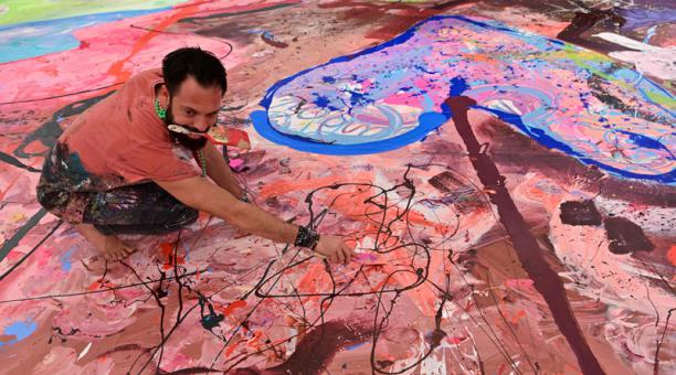 El artista británico Sacha Jafri trabaja en su pintura récord titulada 'El viaje de la humanidad' el 23 de septiembre de 2020. Foto: AFP
