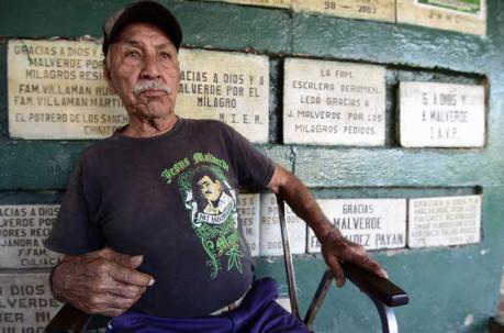 Un vendedor se posa para una fotografía fuera de la capilla de Malverde, que según la leyenda era un bandido de Robin Hood que robó de los ricos y dio a los pobres. Foto: AFP