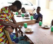 Un niño mira a su niñera mientras toma una comida en el Centro de Bienvenida y Tránsito de Saint Genevieve para los así llamados "niños malditos", ubicado en la ciudad de Katiola, Costa de Marfil. Foto: AFP